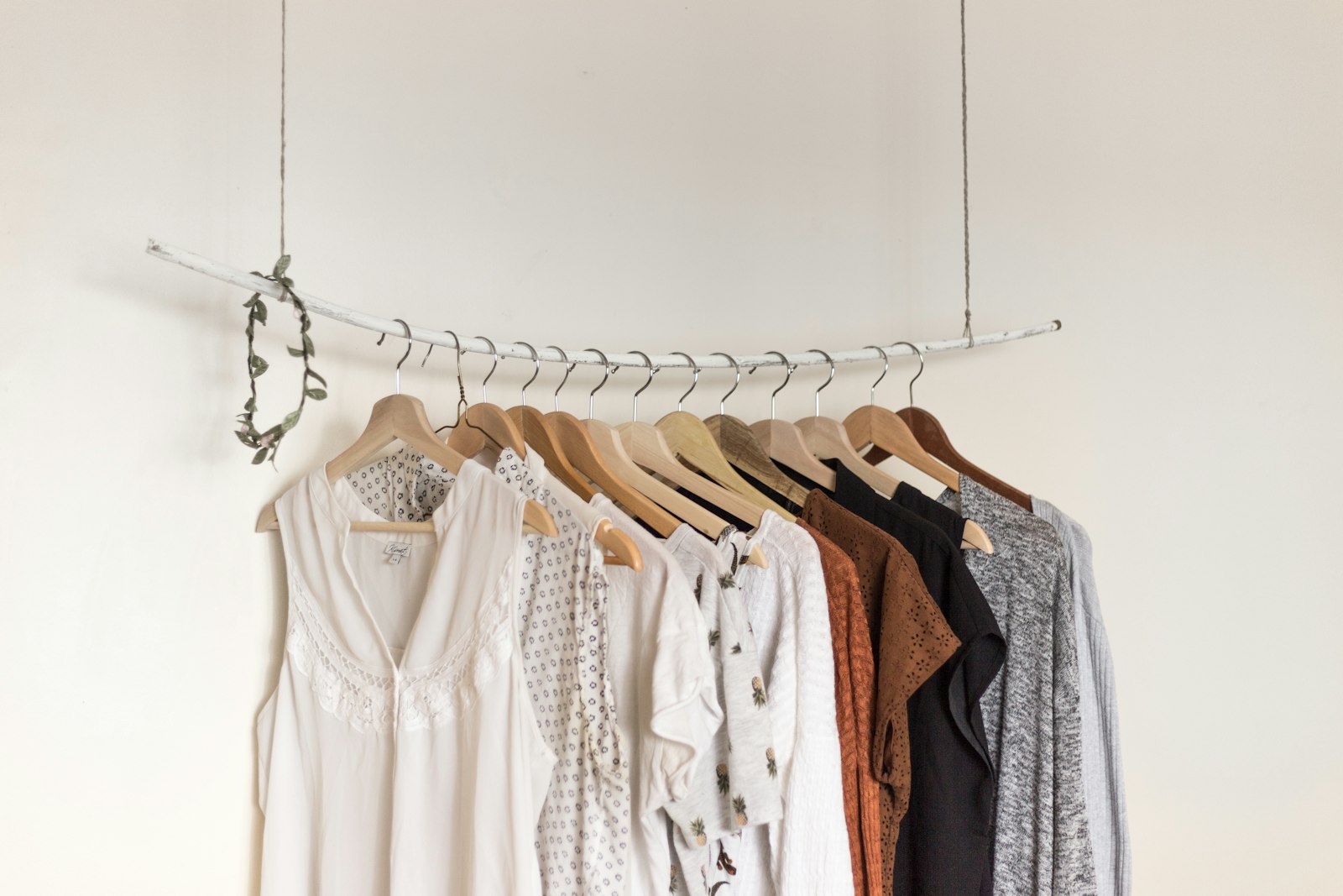 Clothes on wooden hangers suspended from a white branch against a plain wall. It accompanies an article about Naming a product without boxing the company in.