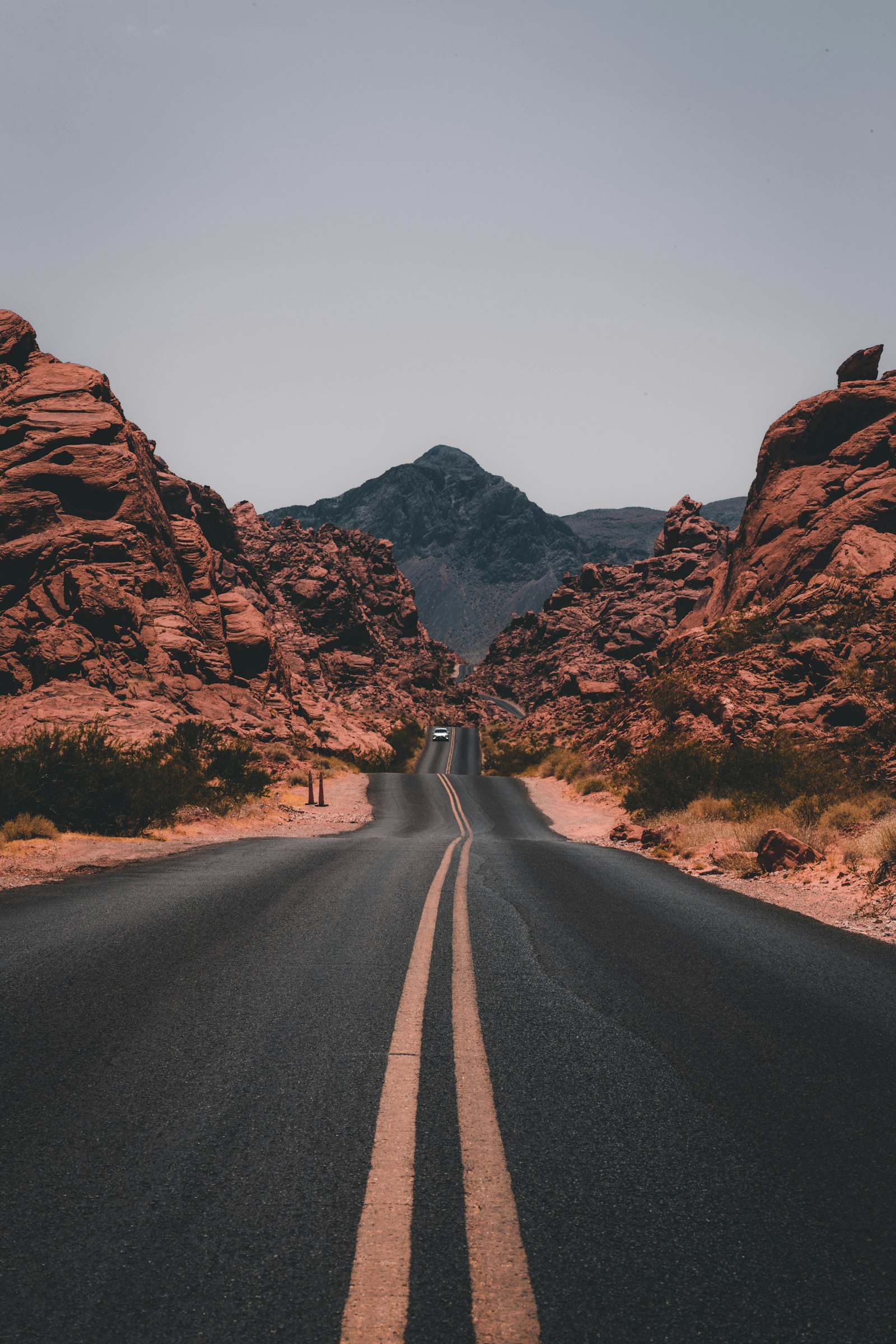 A two-lane road through red rock, with a single car far ahead and a mountain at the end. It accompanies an article about Core Web Vitals in plain language.