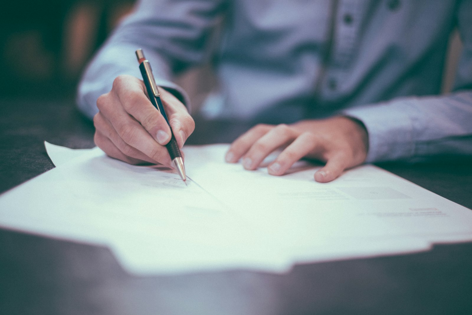 A person in a blue shirt signing a paper document with a pen. It accompanies an article about What a same-day response should mean.
