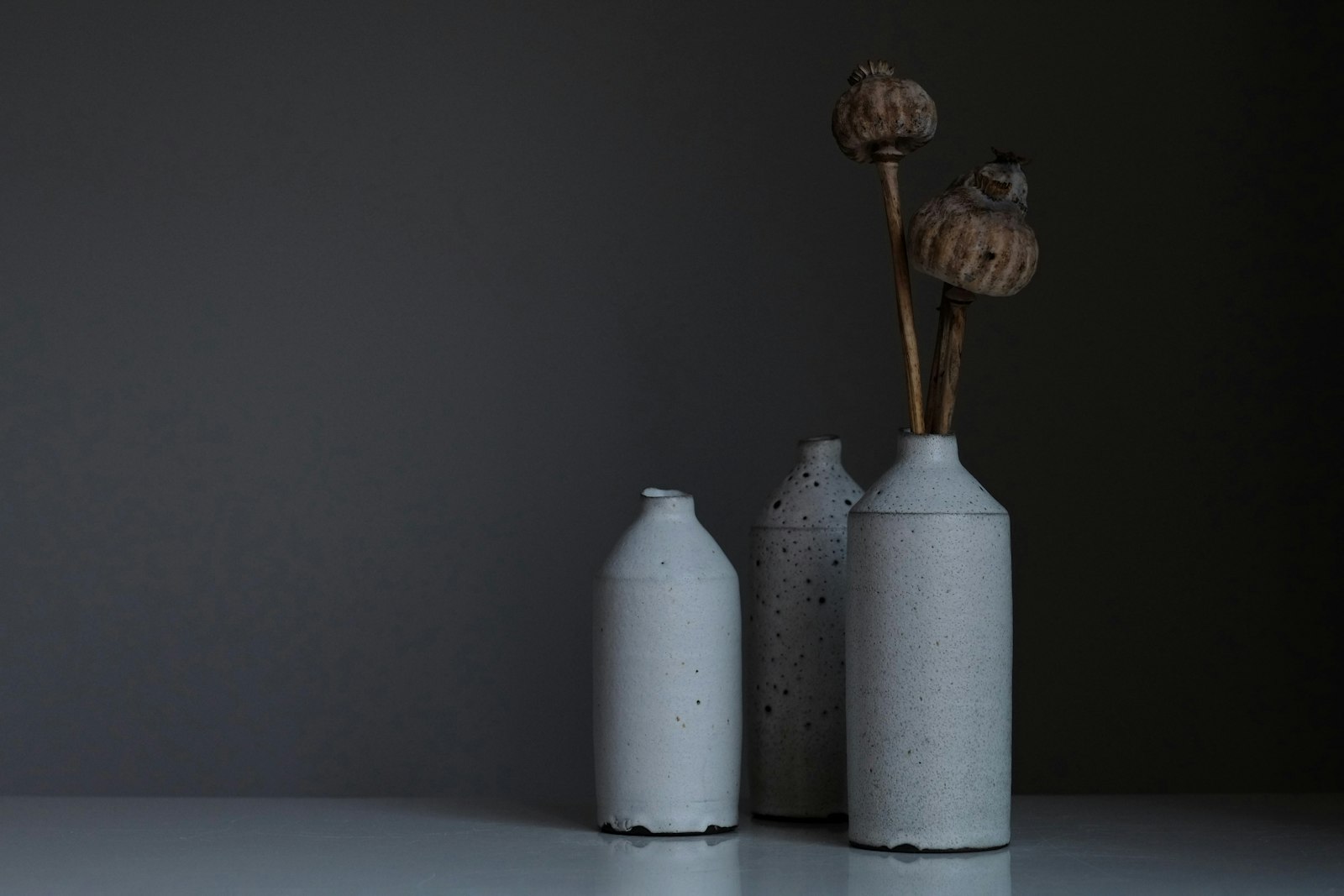 Three pale speckled bottles on a gray surface, two holding dried seed heads. It accompanies an article about What a Telegram bot is good for.