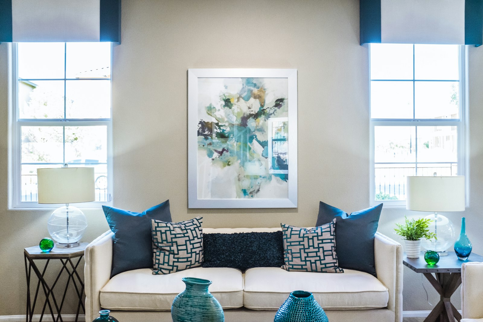 A cream sofa between two bright windows, with a framed abstract painting and teal vases. It accompanies an article about Rebranding without confusing the people who already buy.