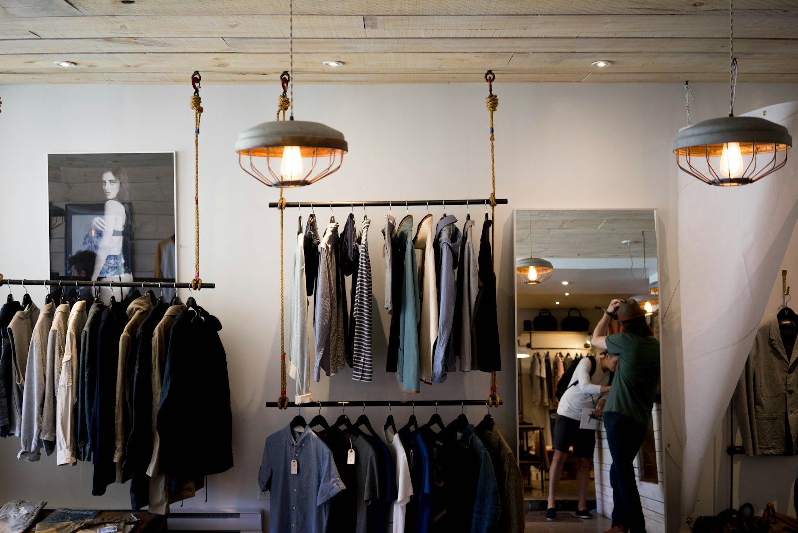 A clothing shop with racks, rope-hung industrial lamps, and a mirror. It accompanies an article about Studio, freelancer, or in-house for a first serious site.