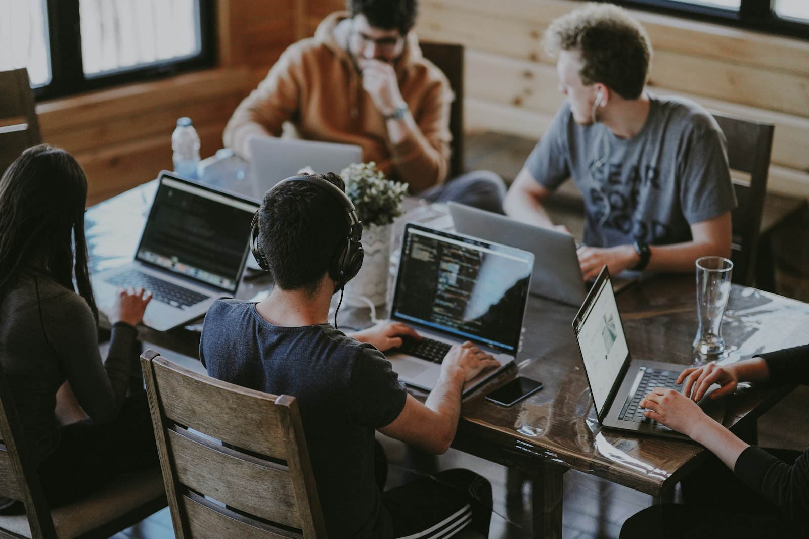 Five people working on laptops around a wooden table. It accompanies an article about Mobile shopping for a brand with a point of view.