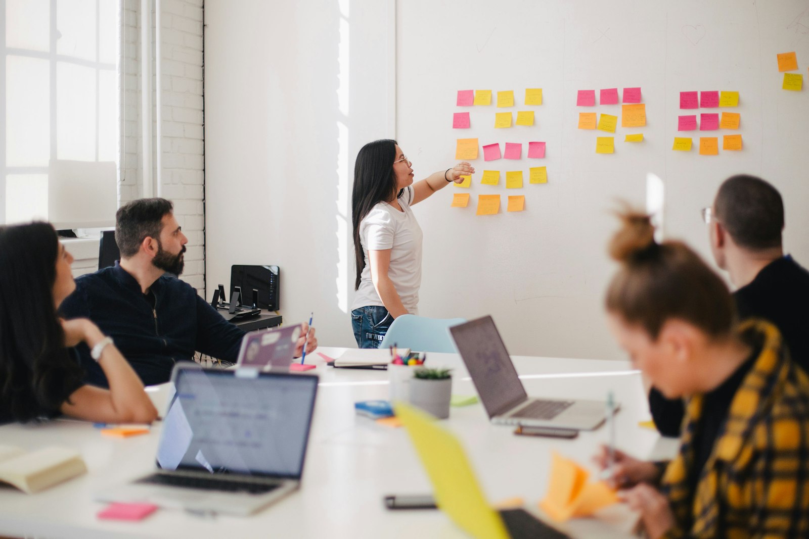 A workshop where one person points at colorful sticky notes while others sit with laptops. It accompanies an article about Why a marketing site should be fast before it is clever.